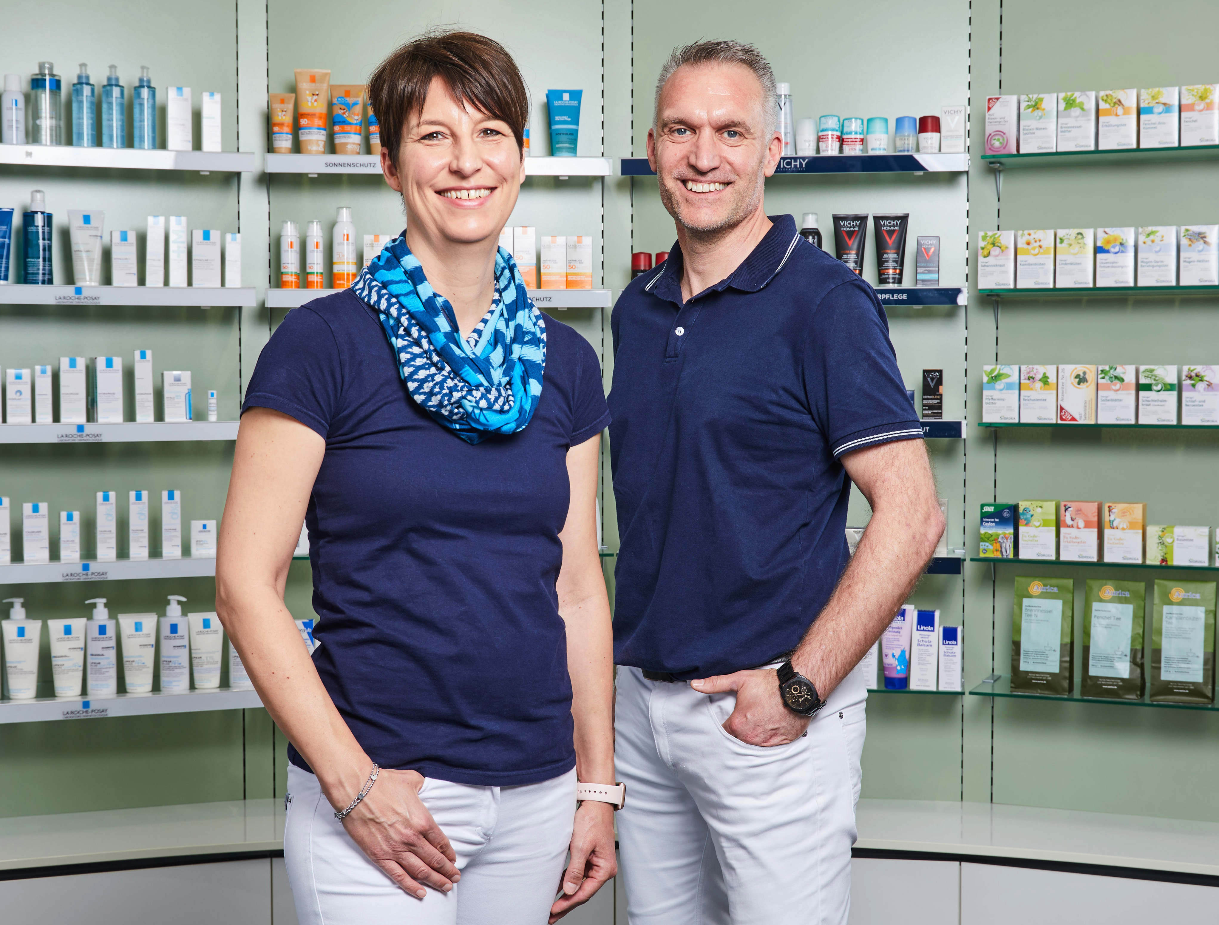 Moderne Innenansicht der Löwen-Apotheke, Inhaber und Apothekerin steht vor einem Medikamentenregal.